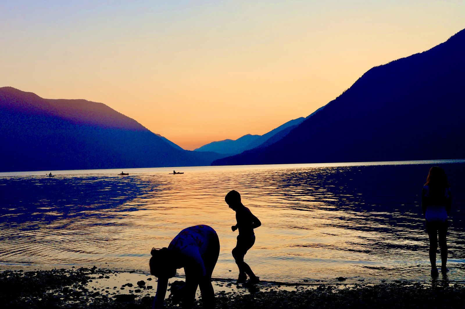 Family silhouettes on a lake at sunset