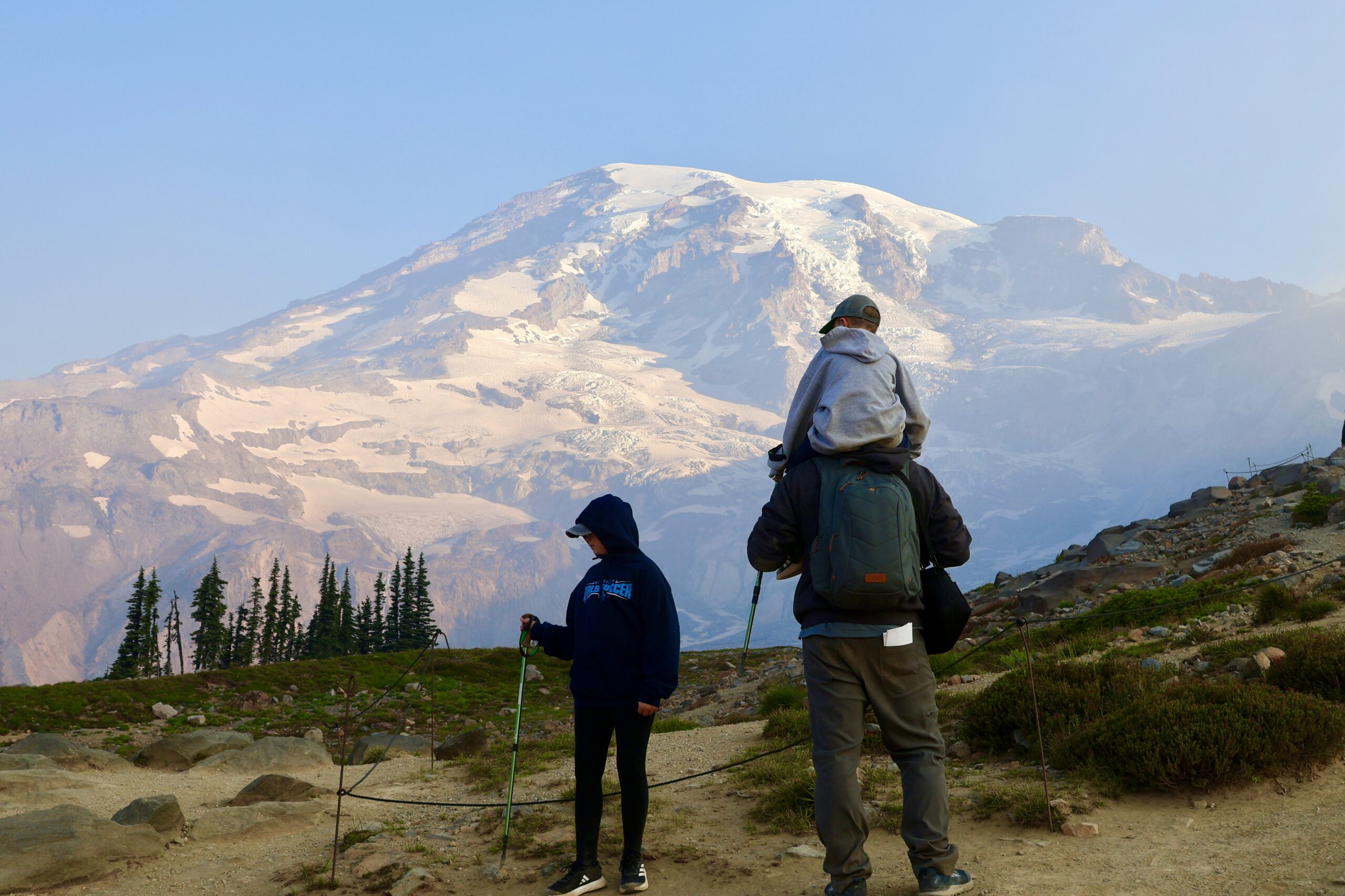 Kids on shoulders facing Mount Rainier, seen from behind