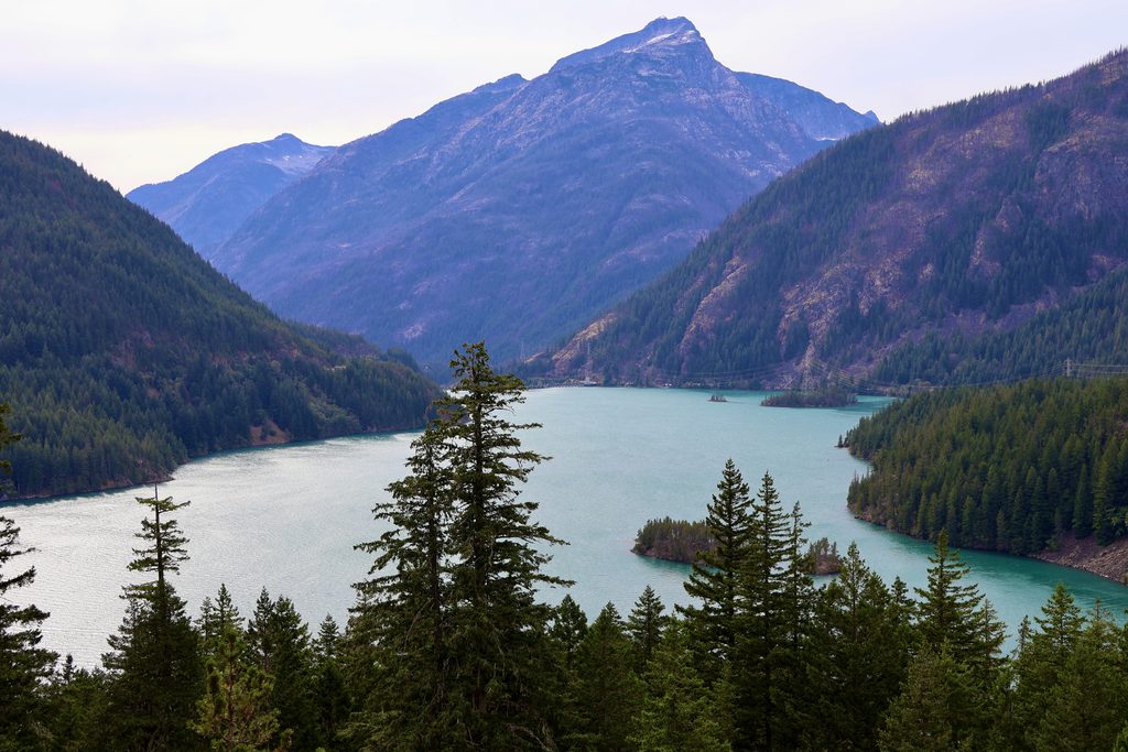 A turquoise lake below forested slopes and a rocky peak in North Cascades